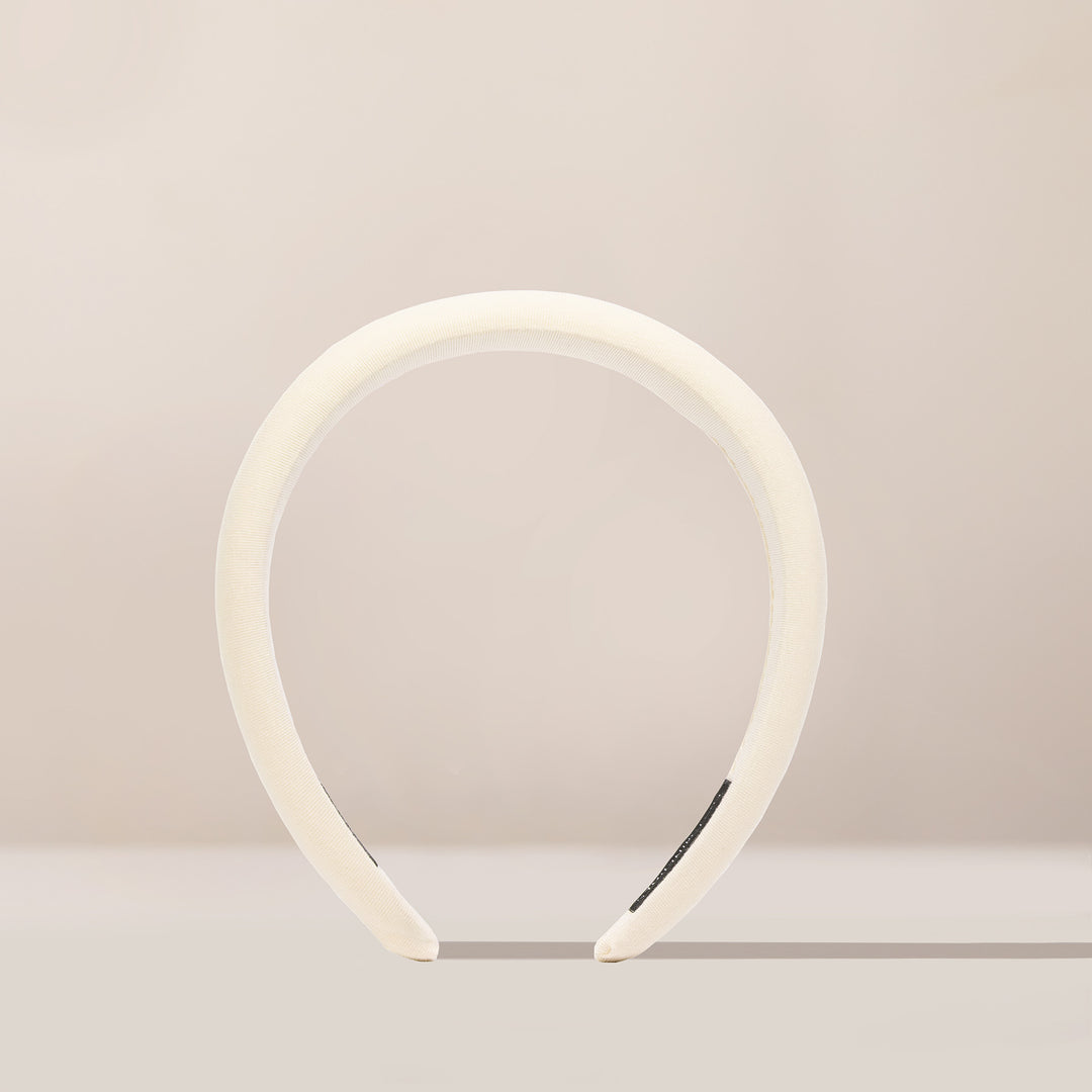 Soft buttercream beige headband made from a smooth, stretchy fabric, featuring a wide band that comfortably fits around the head.