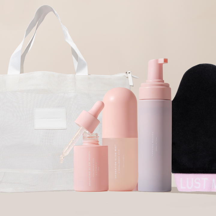 Set of pink skincare products with a white tote bag on a beige background